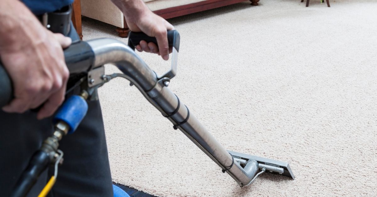 A man cleaning carpet with a Carpet extractor Wand