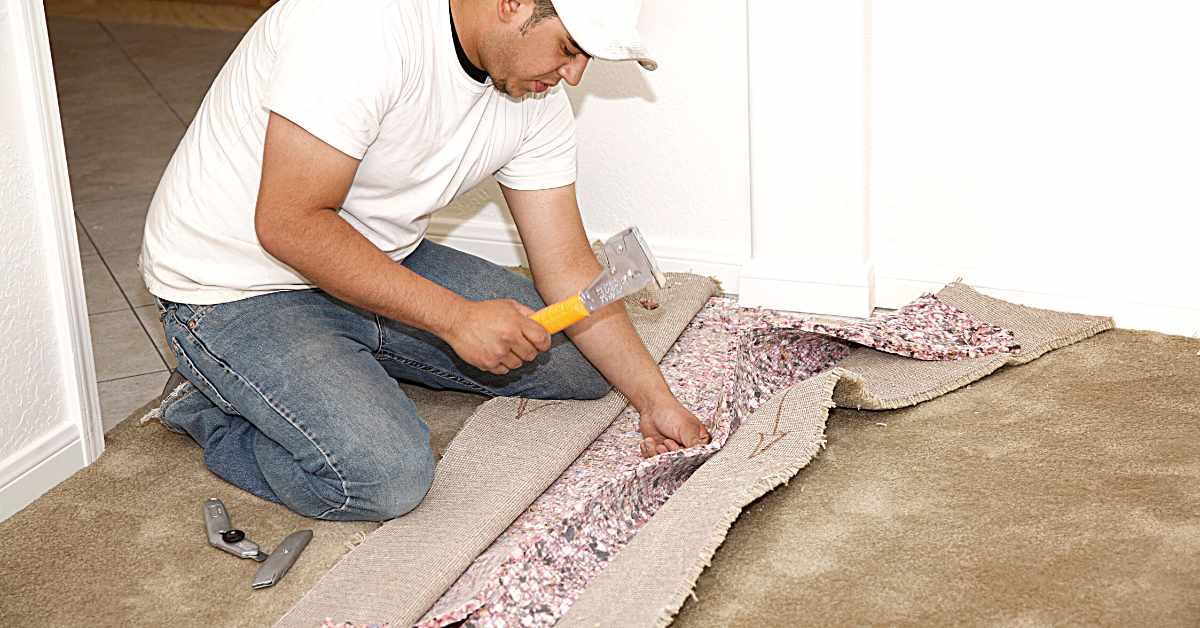 A man replacing carpet in apartment